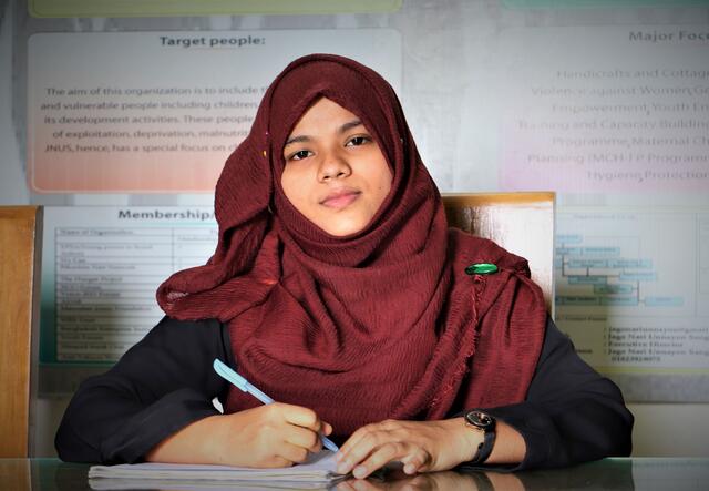 Rima Sultana Rimu, human rights activist, sitting at a table with a pen in her hand