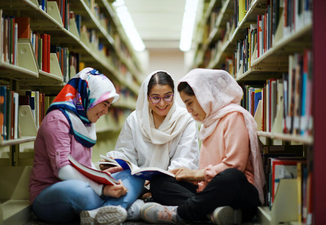 Three Afghan women sit together in a library on the Arizona State University campus.