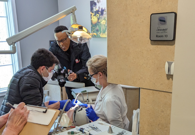 Student Iman and a dental instructor practicing on a dental dummy while Ron Jones films.