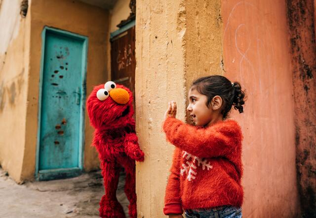 Ett litet barn vinkar till Elmo - pedagogiska media. 