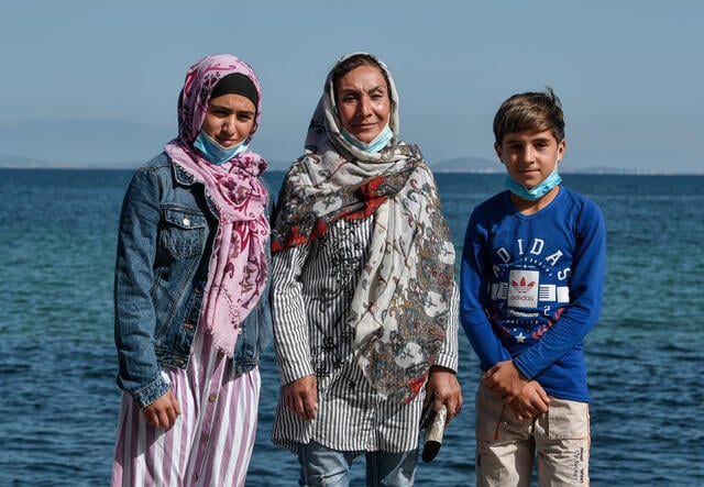 Rahima* stands beside her daughter, Nelofar, and son Ahmad in front of the Mediterranean Sea.
