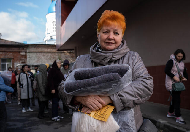 Lyubov schaut in die Kamera und hält dabei eine Decke.