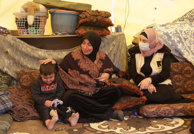 Aysha*, her husband, Nabeel*, and her child, Amjad*, in their tent.