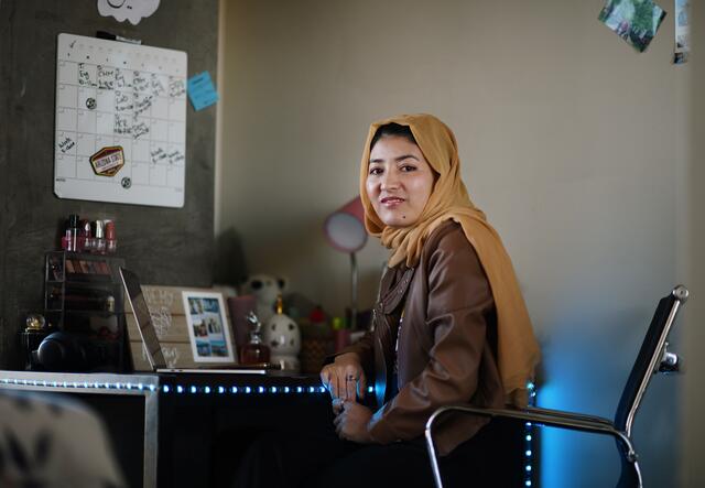 Mansora, ASU Afghan scholar sitting at her desk in her bedroom.