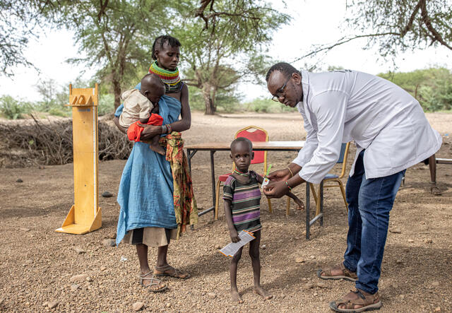 An IRC nutritionist screens a young boy for signs of malnutrition using a specialized tape that fits around the child's arm.