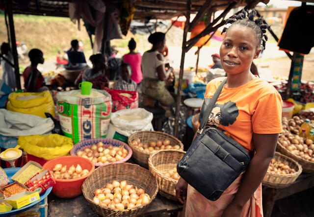 A female market stall holder stands next to her business in Kenema, Sierra Leone