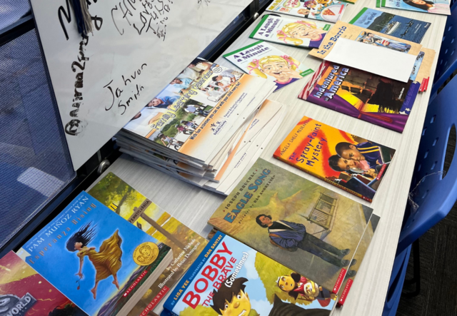 Children's books spread out along a long table inside the mobile IMPACT hub.