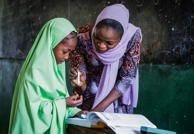 A teacher and a student read together from a text book.