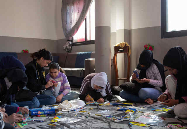  IRC Women's Protection and Empowerment assistant Diana Khoury, 33, helps Ameera*, 15, draw on a tridimensional mask during a drawing activity at IRC’s safe space.