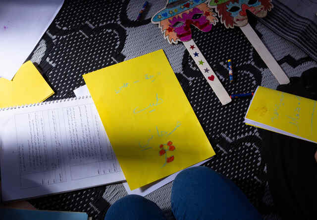 A paper is placed, on the carpet, on which a Syrian refugee girl had written the words “Cheerful - My heart is sweet - Joyful” in Arabic and drawn a red flower during an activity where they had to write their emotions on a paper at the safe space.