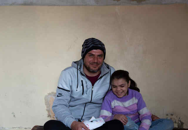 Ameera and her father in the living room of their apartment. Since Ameera loves the beach, he takes her there to spend quality time together collecting seashells.