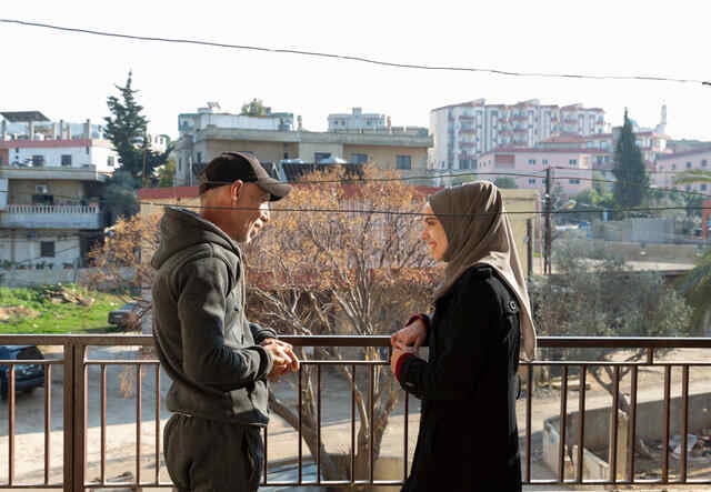 Sabah*, 15, stands on the balcony with her father Hamza*, 45, in their apartment. 