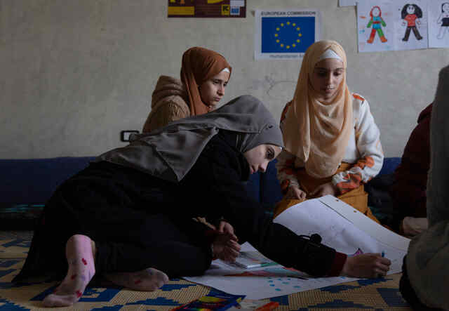  Sabah*, 15, writes and draws on a carton on the floor in the safe space where Syrian refugee girls take part in different kind of activities with the IRC WPE team. 