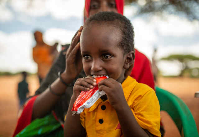 Nasteho Ahmed, 25, håller sin son som äter en näringsrik nötkräm (även kallat färdigt terapeutiskt livsmedel) som RESCUE:s mobila vårdteam delat ut i den somaliska byn Olol.