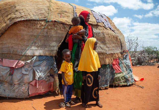 Fartun stands outside her home with her three children.