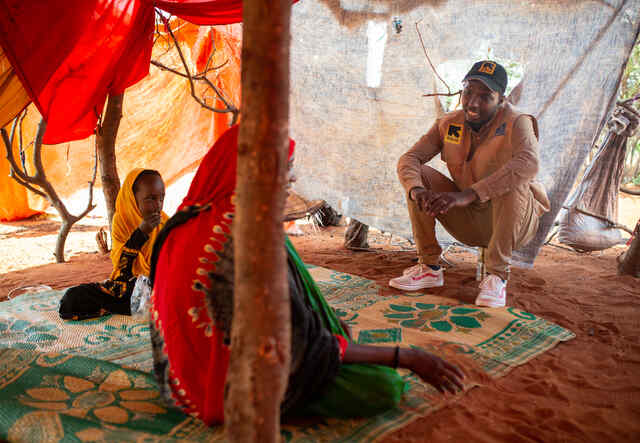 Dr. Ahmed talks with a mother and her children, in their home on the outskirts of Olol village.