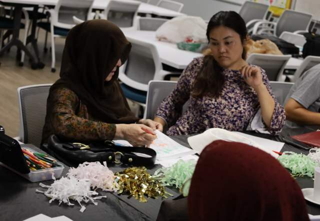 Two participants in the Afghan Senior Social Club talking while drawing.