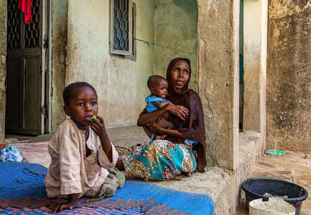 Fatima holds her ninth-month-old son close in her arms. Next to them sits a young boy, Fatima's other son.