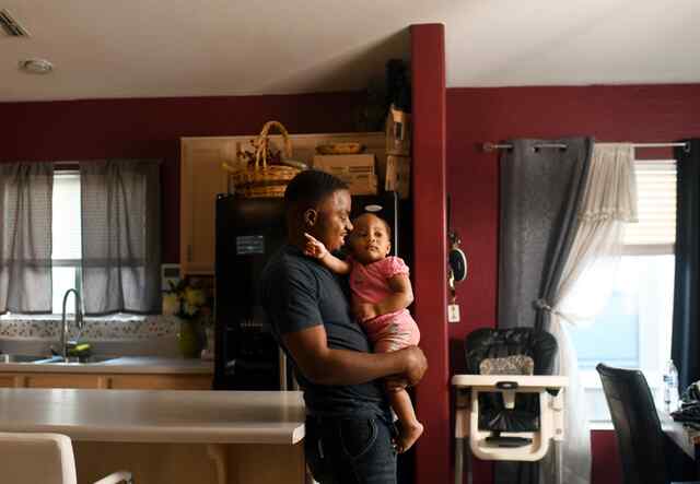 Robert holds his young daughter in their house in Phoenix, Arizona.