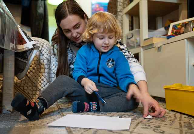 Khrystyna helps her four-year-old son draw and paint in their home.