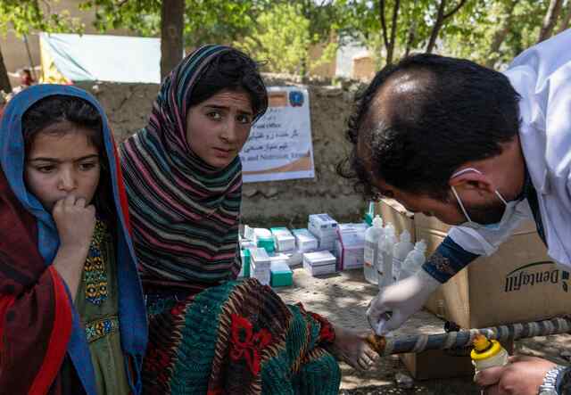 Ein medizinischer IRC-Mitarbeiter kümmert sich um den verletzten Fuß einer jungen Frau in Afghanistan.