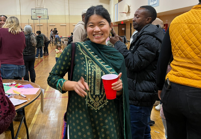 A young woman smiling and holding a drink.