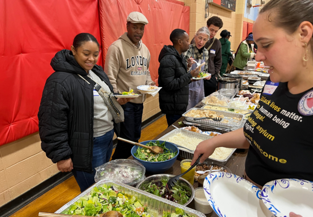 A line of IRC Atlanta staff, volunteers and clients filling their paper plates with food from Mediterranean Bakery.