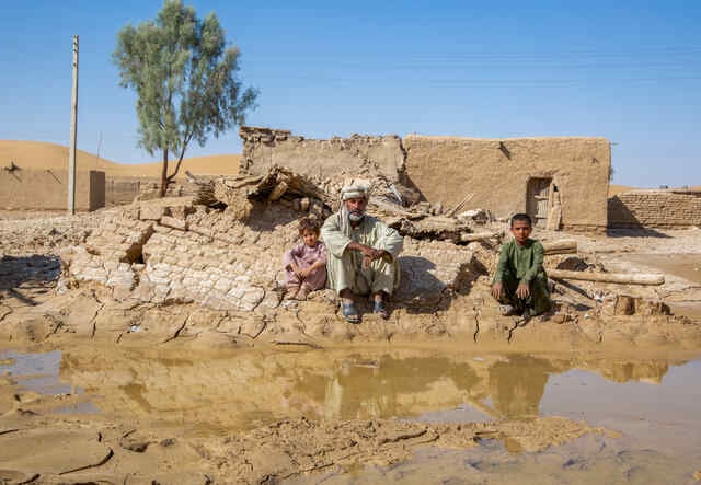 Sakhi und seine Enkelkinder sitzen bei den Überresten ihres Hauses im Dorf Skahi Daru Khan, Nushki, Pakistan.