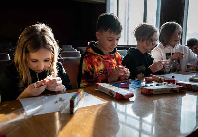 Four children complete a learning activity side by side at an IRC supported Safe Learning and Healing Space in Ukraine.