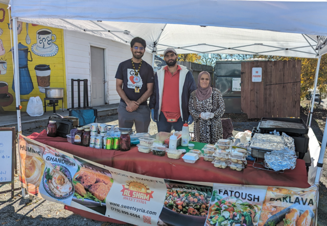 Sultan Minhas and the owners of Al Sham Sweet Syria standing in the Al Sham Sweet Syria pop-up tent.