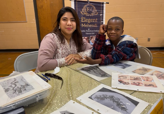 Fiza, owner of Elegant Mehndi, and a child showing off his new henna tattoo