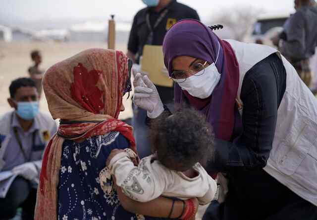 Dr. Waood leans down to meet a young patient in Yemen.