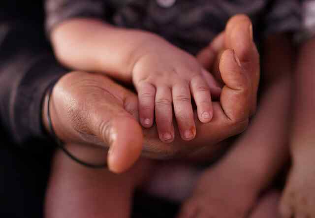 A small Yemeni baby holding her mother's hand