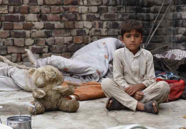 Bilal sits on the ground next to his teddy bear, who looks a little worse for wear after being saved from the flood in Pakistan.