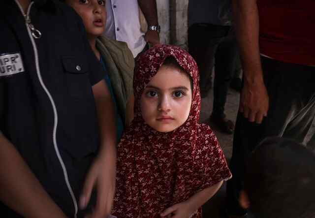 A Palestinian girl walks with her father after the Friday prayer in Gaza on August 4, 2023