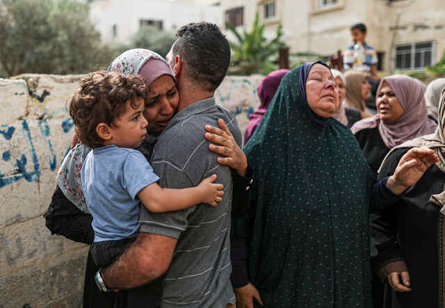 Palestinians are pictured hugging and mourning together.