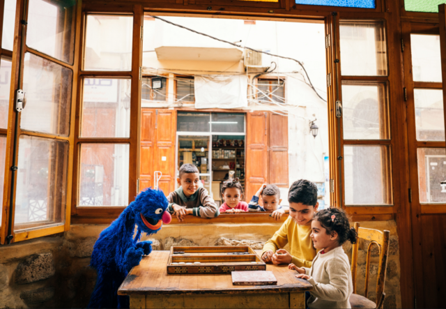 Promotional picture for Ahlan Simsim of Sesame Street character playing with children