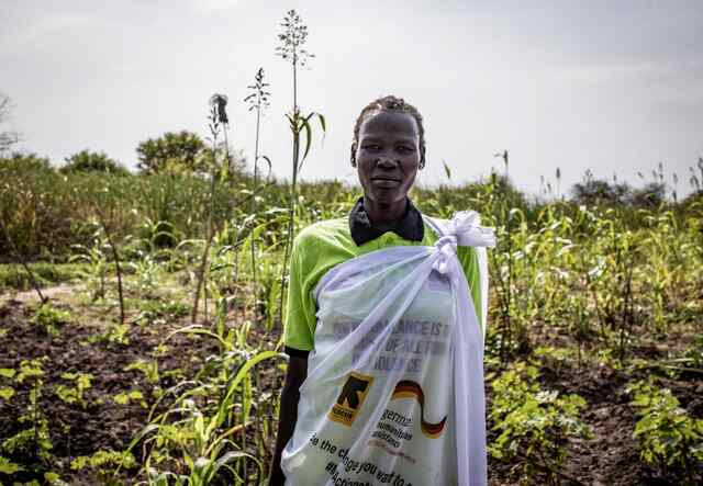 Nyapar stands tall, posing for a portrait in an agricultural field in South Sudan.
