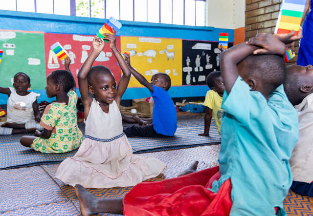 Students in Uganda hold LEGO bricks above their heads.