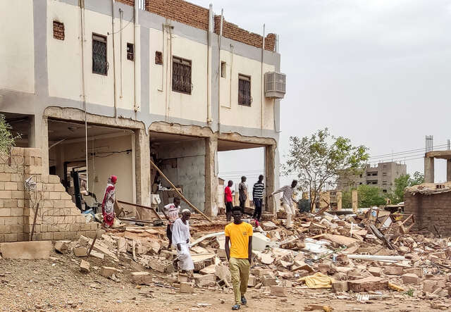 People inspect the rubble at a house that was hit by an artillery shell.