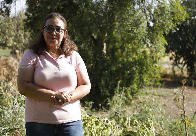 Midya stands proudly next to green crops in her field in Northeast Syria. 