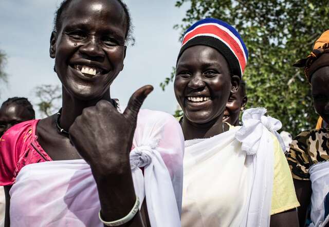 Participants at an IRC Women's Center in Kanyhial, South Sudan stand together for a photo. They smile while giving a "thumbs-up" to the camera.