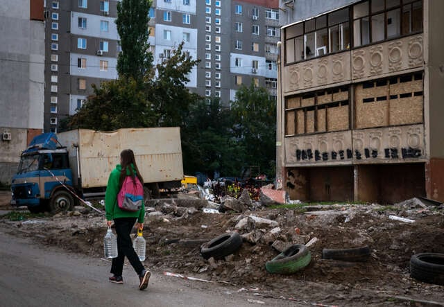 En kvinna går igenom ett bostadsområde som skadats av en misilattack i Mykolaiv, Ukraina.