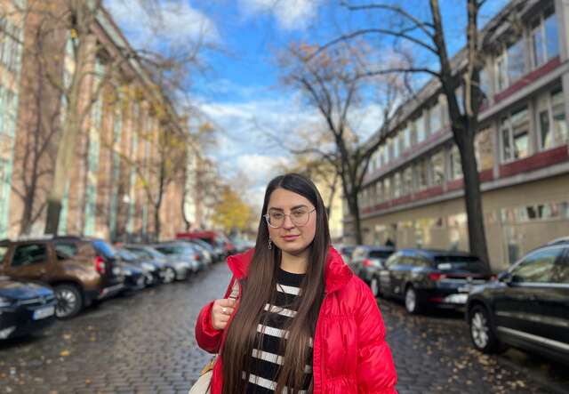 Eine Frau in einer roten Jacke steht auf einer Straße.