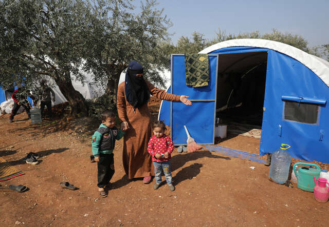 En mamma, Dania, står framför ett provisoriskt tält som hon och hennes familj har bott i sedan jordbävningen i Syrien och Turkiet. 