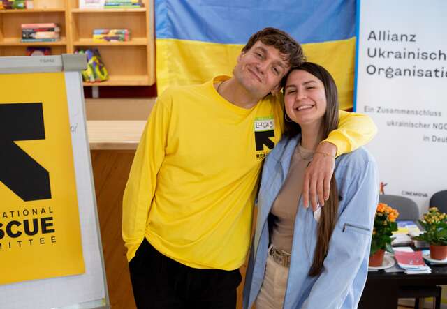 Ein Mann und eine Frau posieren vor einem gelben Banner.