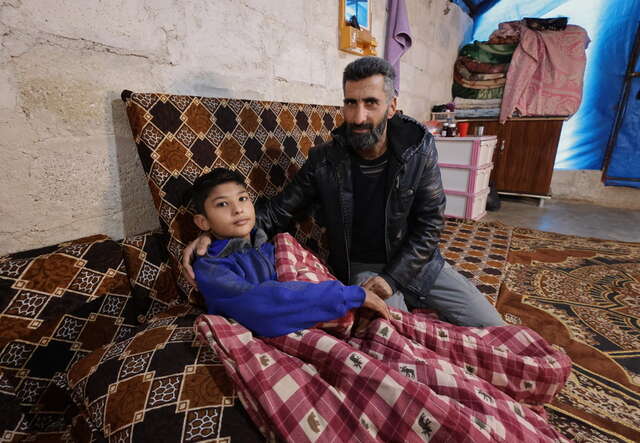 Yahya*, 15, with his father Khaled* in their tent.