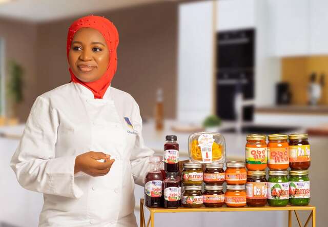 Nimota poses for a photo next to a display table full of her hand-crafted sauces.