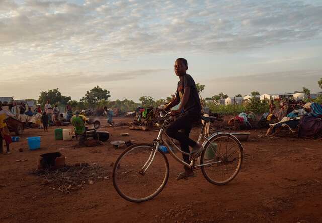 A boy rides a bike through a camp for internally displaced people in Burkina Faso.