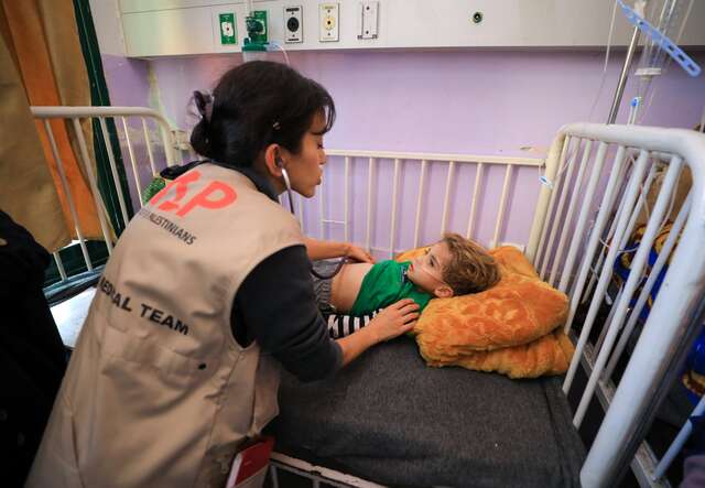 Dr. Seema Jilani leans over a bed and tends to a young child.